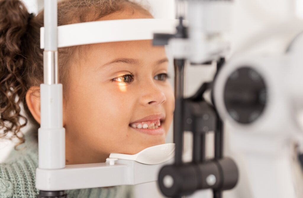 A child rests their chin on a support while having their eye examined with a slit lamp.