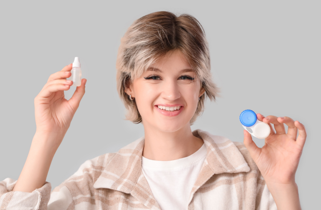 A happy adult holds up contact lenses and artificial tears.