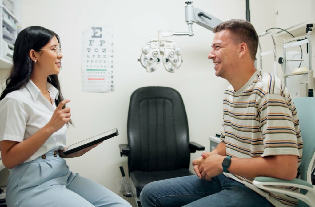 An optometrist sits with a patient in a bright office and explains the patient's options for treating farsightedness.