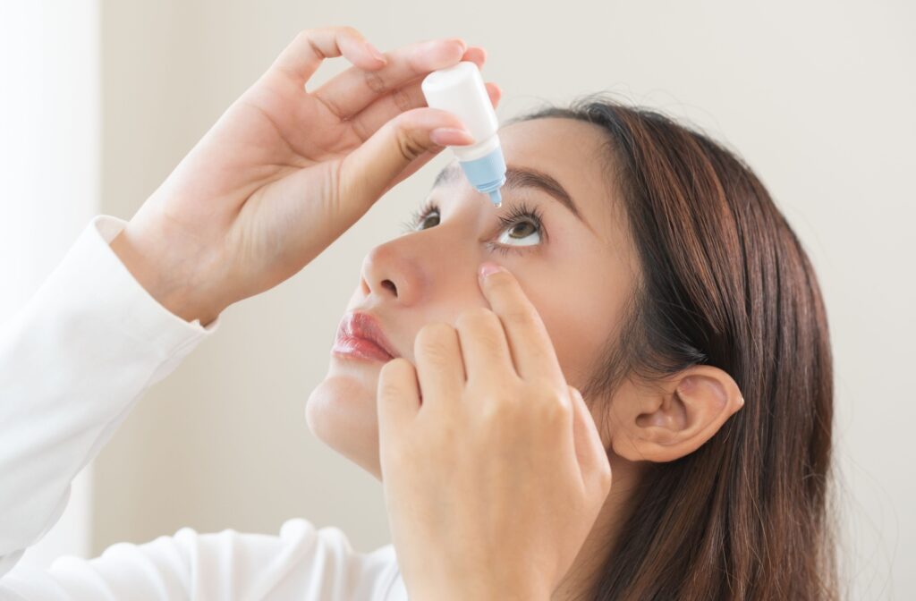 Person gently pulling down lower eyelid while applying eye drops into the eye.