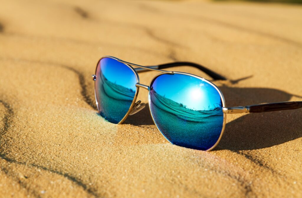 A pair of polarized, UV protection sunglasses sitting in sand