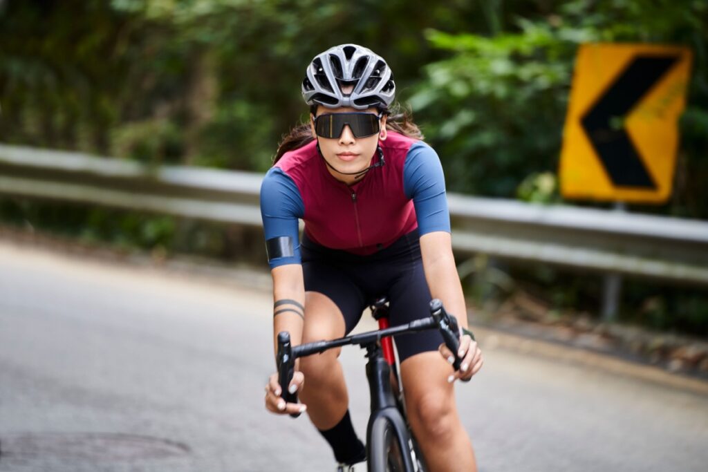 A person outside riding their bike, wearing sport specific sunglasses to protect their eye health and vision.